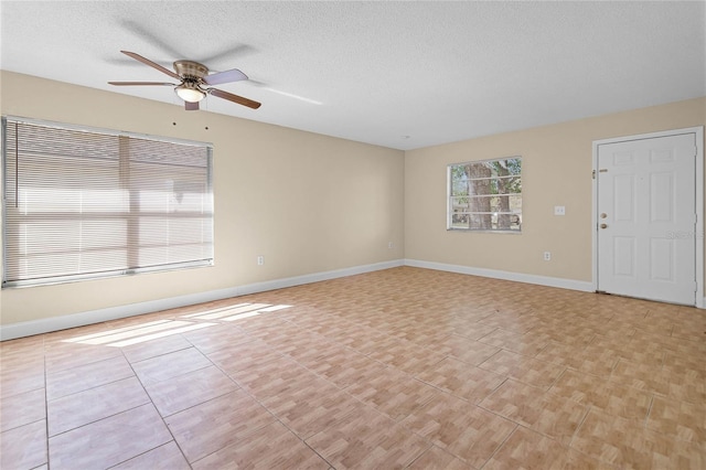 unfurnished room featuring light tile patterned floors, ceiling fan, a textured ceiling, and baseboards