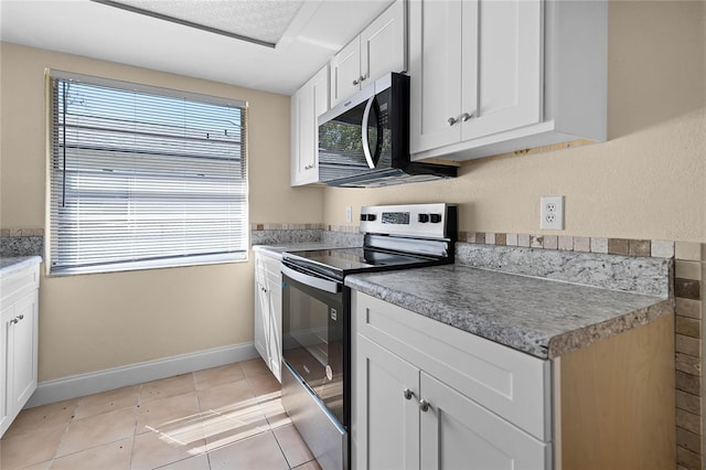 kitchen featuring stainless steel appliances, baseboards, white cabinets, and light tile patterned flooring