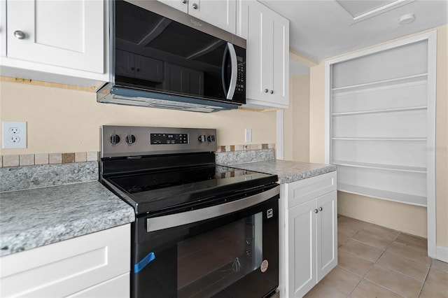 kitchen featuring light tile patterned floors, electric range oven, light countertops, white cabinets, and stainless steel microwave