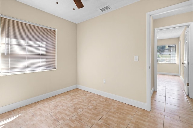 empty room with a ceiling fan, light tile patterned floors, baseboards, and visible vents