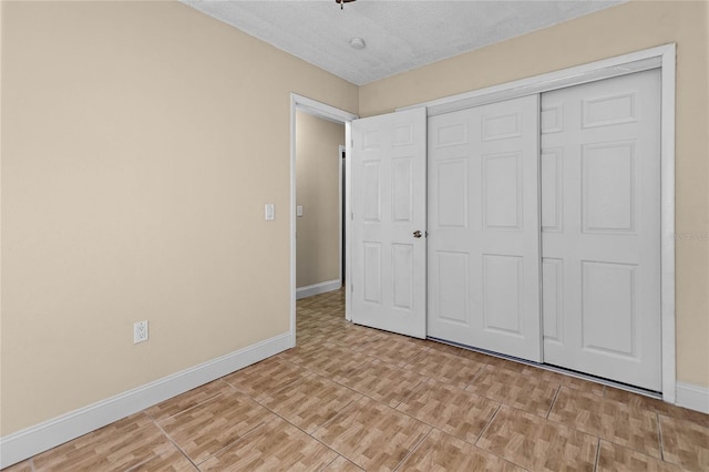 unfurnished bedroom featuring baseboards, a closet, and a textured ceiling