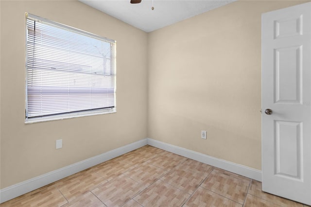 spare room with light tile patterned flooring, a ceiling fan, and baseboards