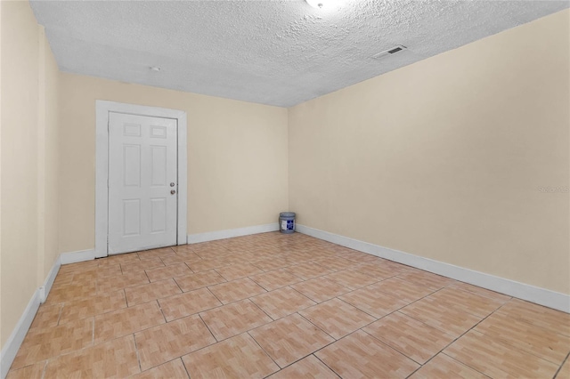 unfurnished room featuring baseboards, visible vents, and a textured ceiling