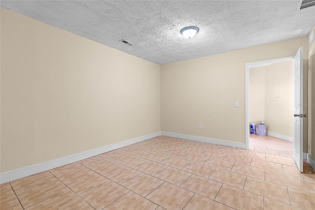 spare room with visible vents, baseboards, a textured ceiling, and light tile patterned flooring