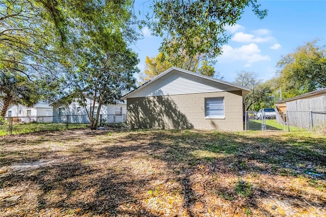 view of property exterior with concrete block siding, a gate, and fence