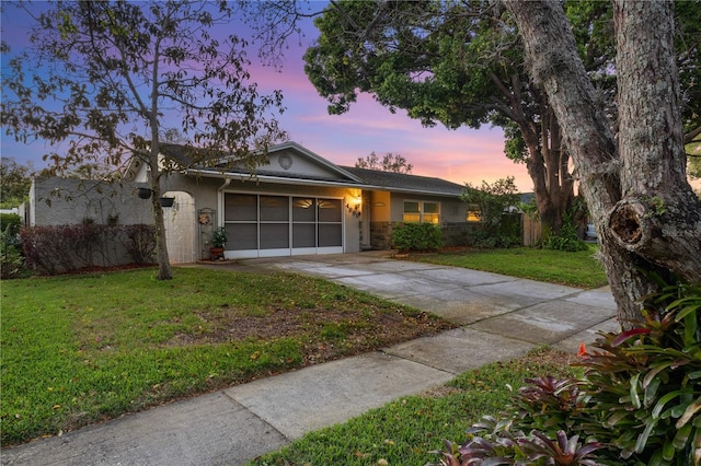 ranch-style home with stucco siding, driveway, stone siding, a yard, and a garage