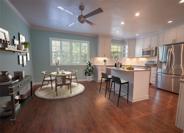 kitchen with dark wood finished floors, a kitchen breakfast bar, white cabinets, and stainless steel appliances