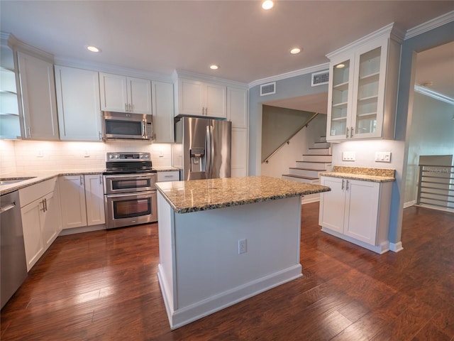 kitchen featuring light stone counters, visible vents, appliances with stainless steel finishes, and glass insert cabinets