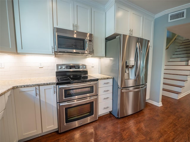 kitchen with visible vents, backsplash, appliances with stainless steel finishes, light stone countertops, and dark wood-style flooring