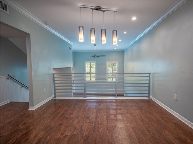 empty room featuring visible vents, wood finished floors, baseboards, and ornamental molding