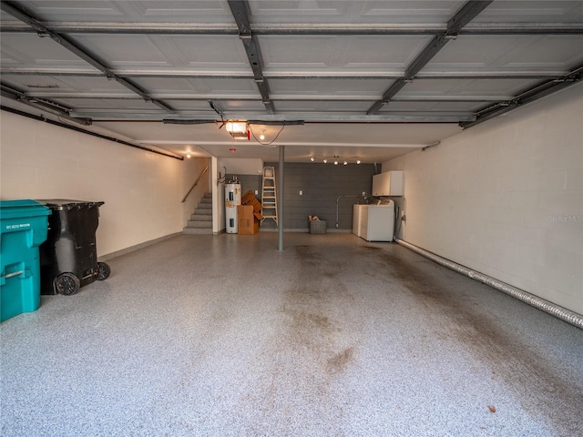 garage featuring concrete block wall, a garage door opener, water heater, and washer and clothes dryer