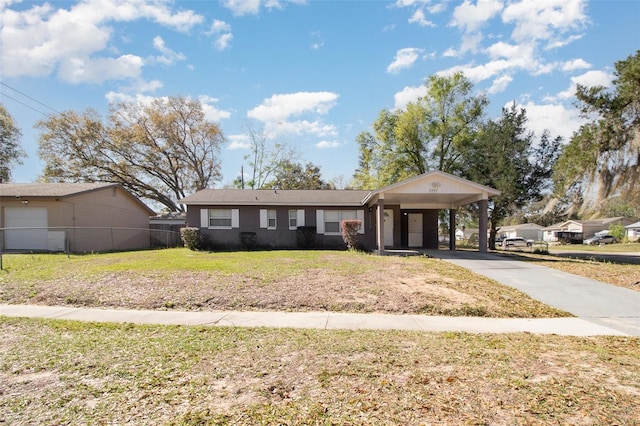 view of front of house with an attached carport, concrete driveway, a front yard, and fence