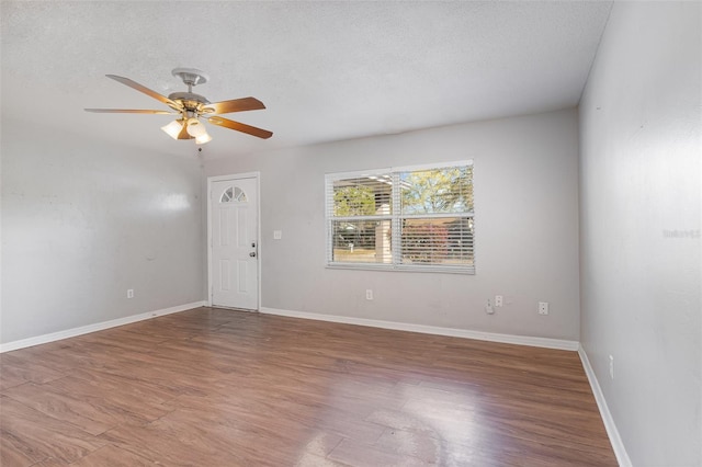 empty room with baseboards, a textured ceiling, wood finished floors, and a ceiling fan