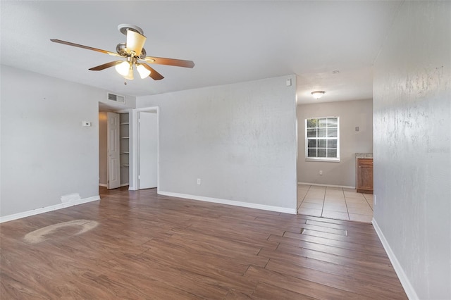 empty room featuring visible vents, baseboards, wood finished floors, and a ceiling fan