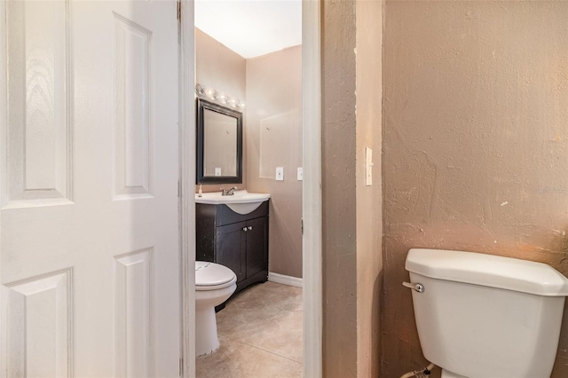 half bath featuring a textured wall, toilet, vanity, and tile patterned flooring