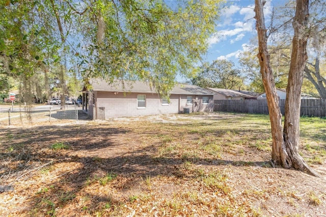 back of house featuring central air condition unit, fence private yard, and concrete block siding