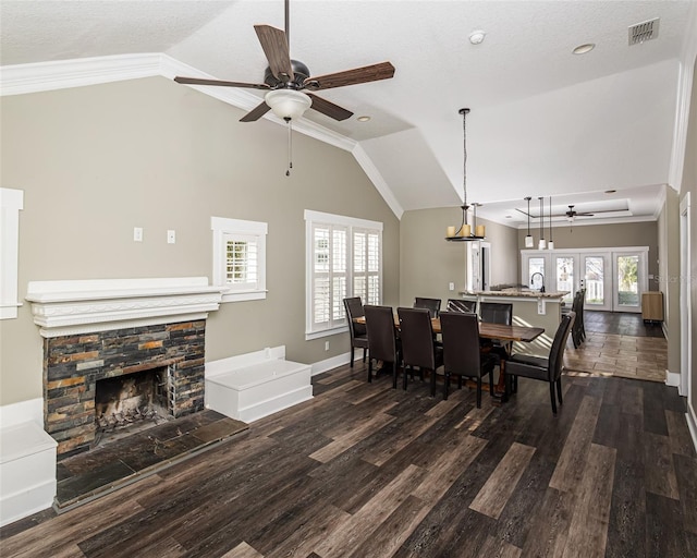 dining space featuring visible vents, a fireplace, lofted ceiling, and dark wood-style flooring