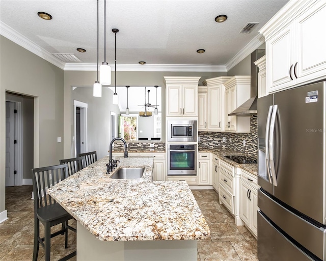 kitchen featuring a sink, appliances with stainless steel finishes, a kitchen bar, wall chimney range hood, and tasteful backsplash