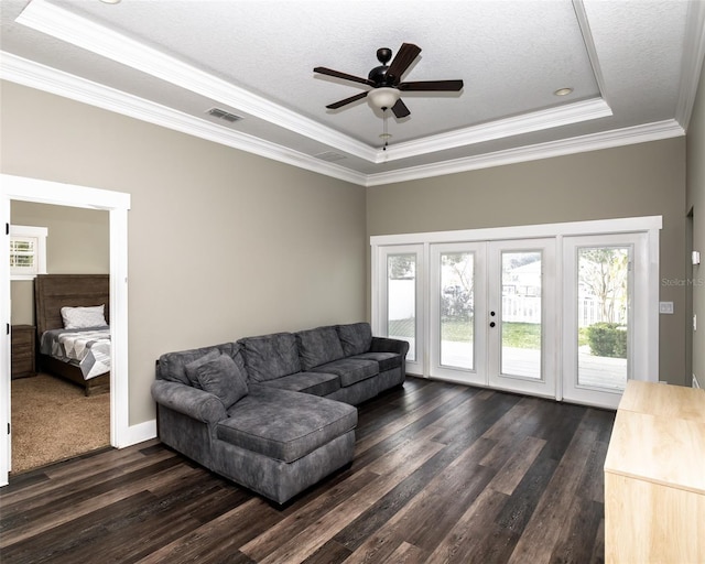 living room featuring visible vents, dark wood-type flooring, french doors, crown molding, and a raised ceiling