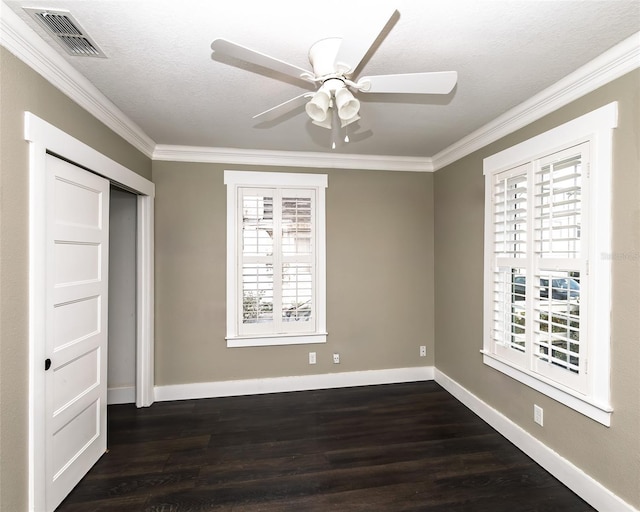 unfurnished bedroom featuring dark wood finished floors, crown molding, baseboards, and visible vents