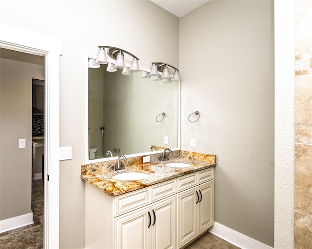 bathroom with double vanity, baseboards, tile patterned floors, and a sink