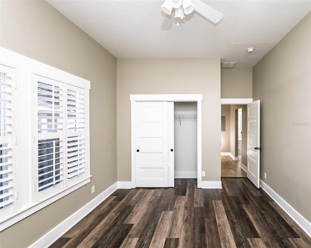 unfurnished bedroom with baseboards, a closet, dark wood-style floors, a textured ceiling, and a ceiling fan