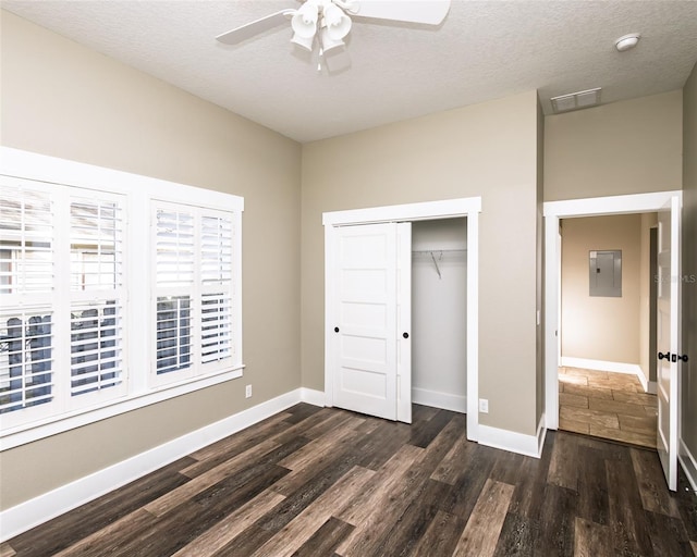 unfurnished bedroom featuring ceiling fan, baseboards, a closet, a textured ceiling, and dark wood-style flooring