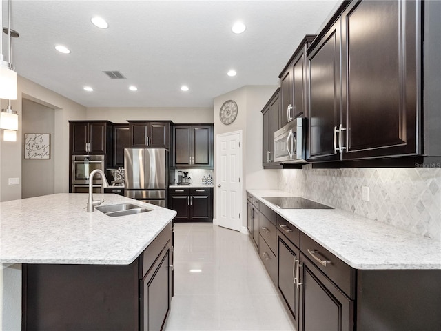 kitchen with a center island with sink, visible vents, a sink, stainless steel appliances, and tasteful backsplash