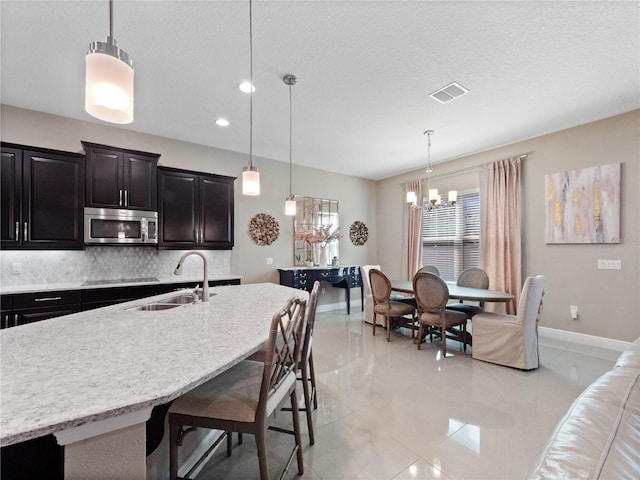 kitchen featuring visible vents, a notable chandelier, a sink, stainless steel microwave, and tasteful backsplash