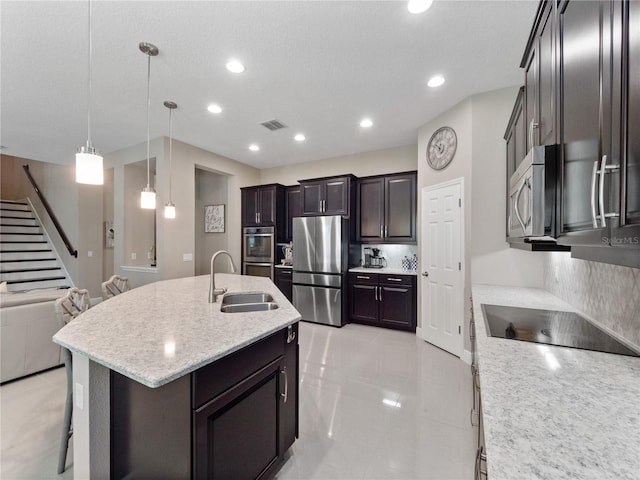 kitchen featuring visible vents, an island with sink, hanging light fixtures, stainless steel appliances, and a sink