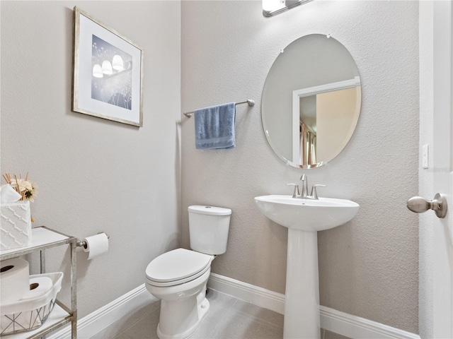 bathroom with tile patterned floors, baseboards, toilet, and a sink