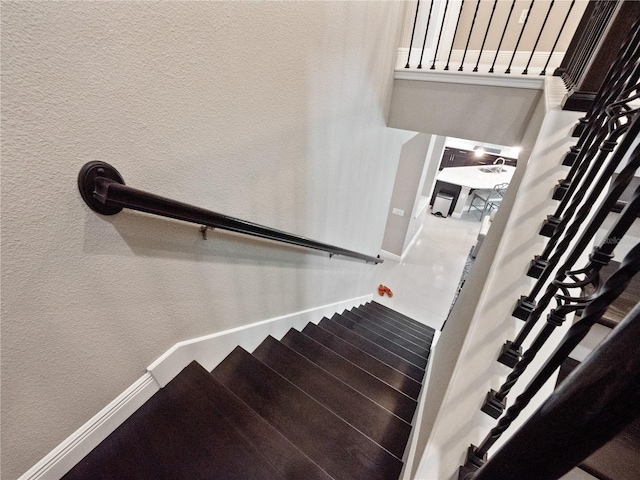 stairway with baseboards and a textured wall