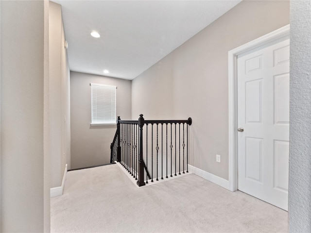 hallway featuring recessed lighting, baseboards, an upstairs landing, and carpet