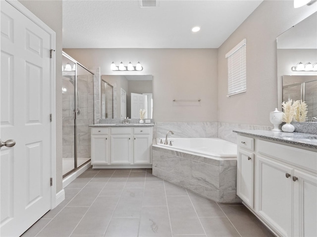 full bath with a garden tub, two vanities, a shower stall, and tile patterned flooring