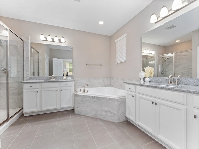 bathroom featuring visible vents, two vanities, a stall shower, a sink, and a bath