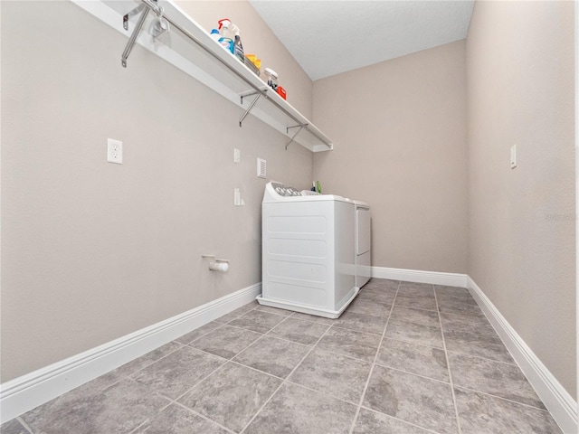 clothes washing area with light tile patterned floors, laundry area, washer and dryer, and baseboards