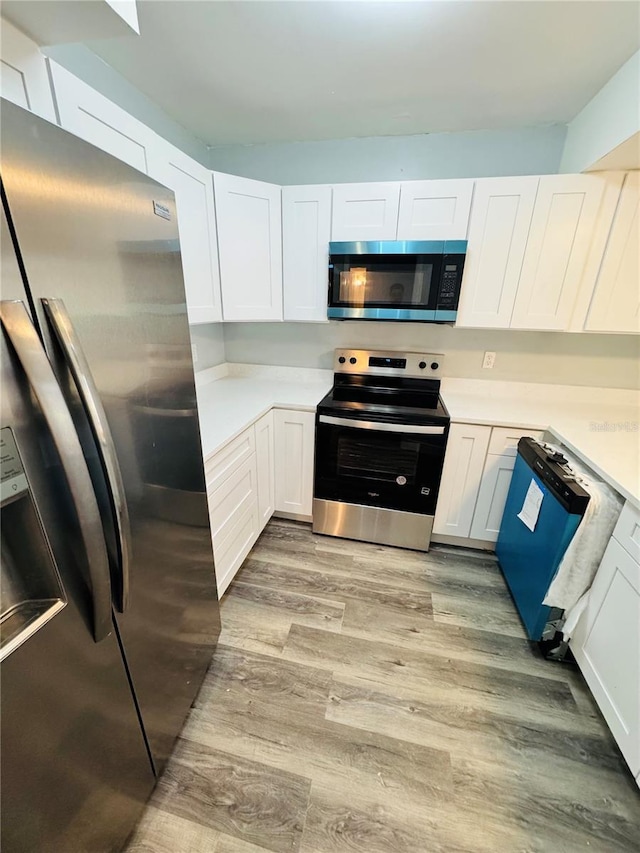 4100 Player Cir Unit 101, Orlando, FL 32808 - kitchen with white cabinetry, light countertops, light wood-style floors, and stainless steel appliances