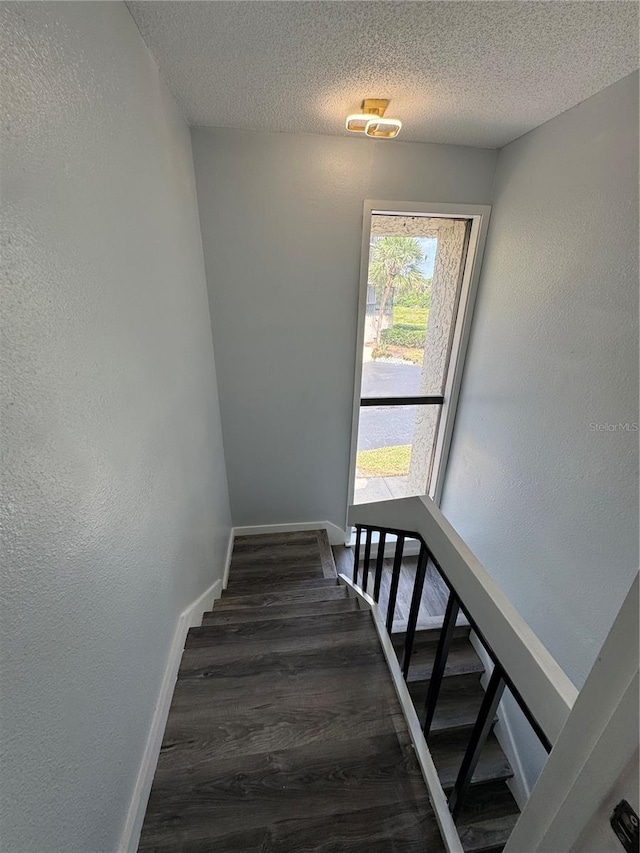 4100 Player Cir Unit 101, Orlando, FL 32808 - staircase featuring wood finished floors, baseboards, a textured wall, and a textured ceiling