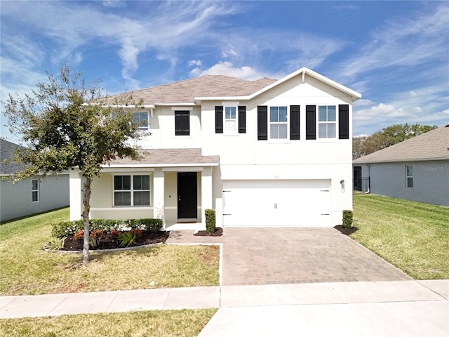 traditional-style home featuring a front lawn, decorative driveway, an attached garage, and stucco siding