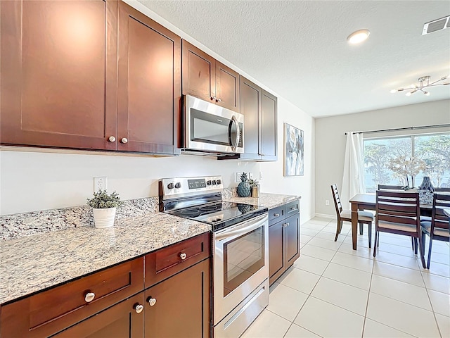 3279 Landing Vw, Tavares, FL 32778 - kitchen with visible vents, light tile patterned floors, appliances with stainless steel finishes, a textured ceiling, and light stone countertops