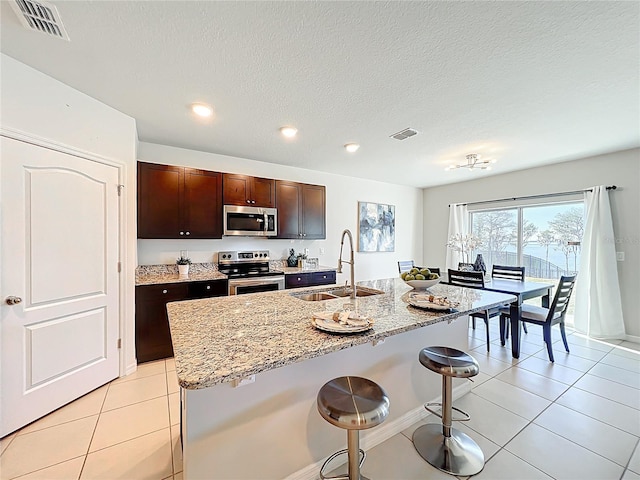 3279 Landing Vw, Tavares, FL 32778 - kitchen with visible vents, a breakfast bar, appliances with stainless steel finishes, light tile patterned flooring, and a sink