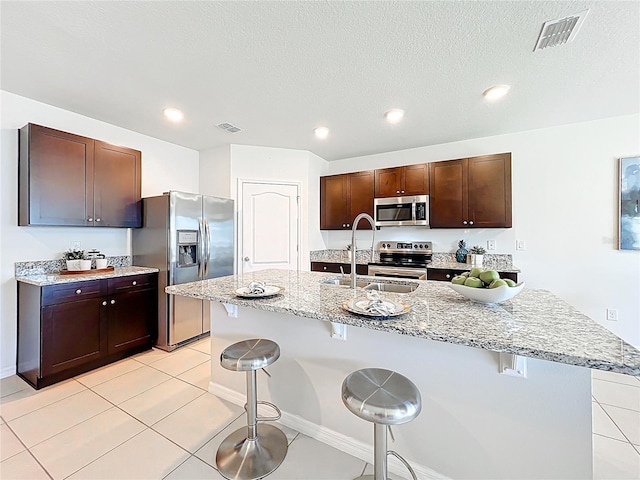 3279 Landing Vw, Tavares, FL 32778 - kitchen with light stone countertops, visible vents, a breakfast bar, appliances with stainless steel finishes, and a sink