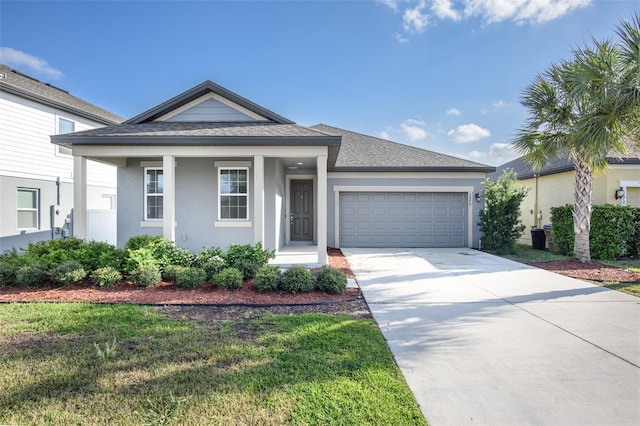 view of front facade featuring a shingled roof, a front lawn, concrete driveway, stucco siding, and a garage