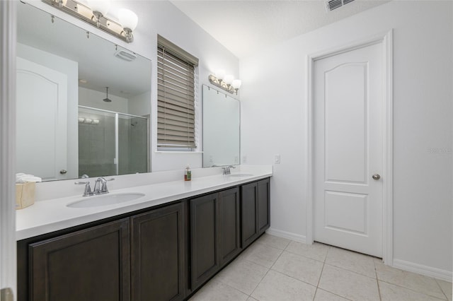 bathroom with tile patterned flooring, a shower stall, double vanity, and a sink