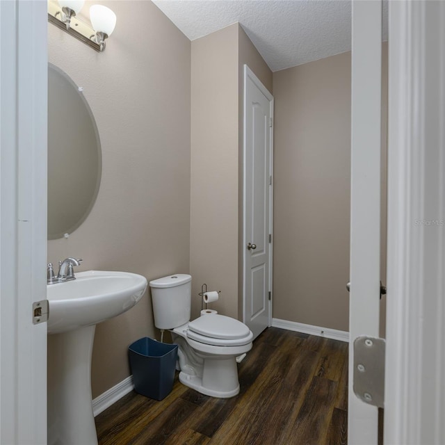 bathroom with a sink, toilet, baseboards, and wood finished floors