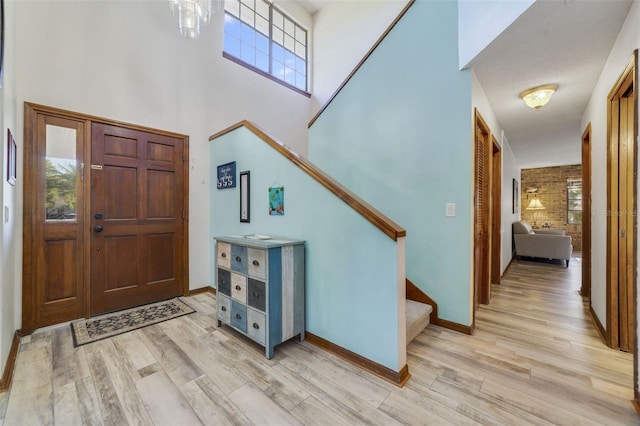 foyer featuring stairway, light wood-style floors, a high ceiling, and baseboards