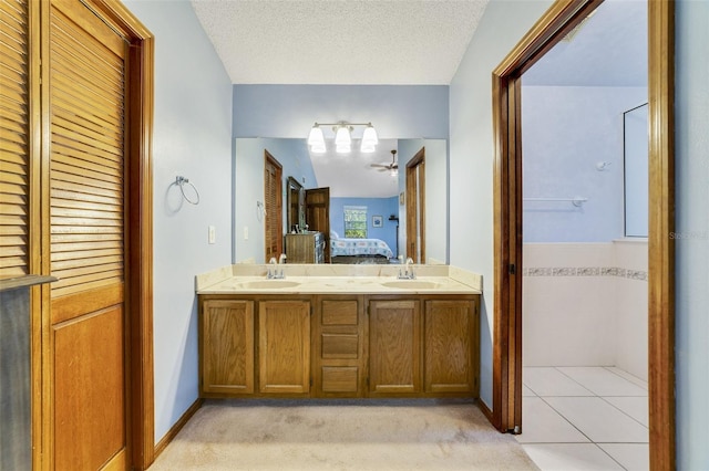 bathroom with a sink, a textured ceiling, double vanity, and connected bathroom