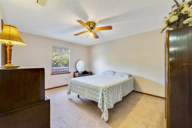 carpeted bedroom featuring visible vents, baseboards, a textured ceiling, and a ceiling fan