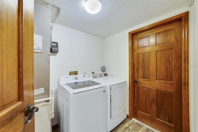 laundry area featuring washing machine and clothes dryer, laundry area, light wood finished floors, and a textured ceiling