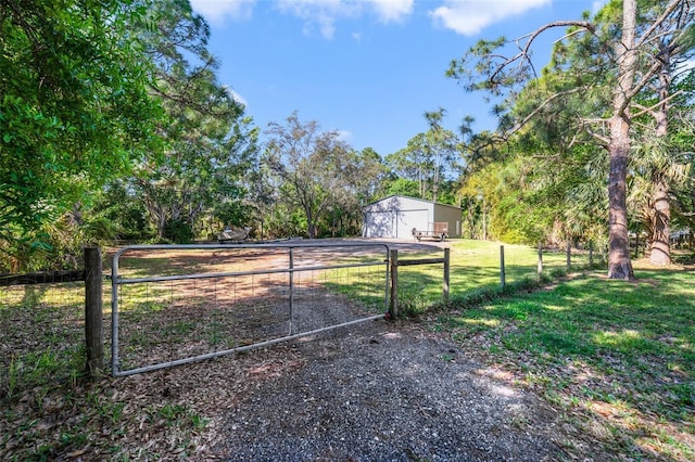 view of yard featuring an outbuilding, driveway, a gate, a detached garage, and fence